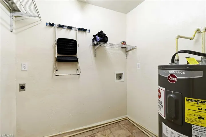 Clothes washing area featuring hookup for a washing machine, electric water heater, and electric dryer hookup