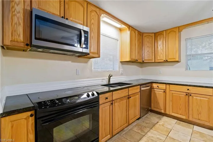 Kitchen with dark stone countertops, sink, and stainless steel appliances