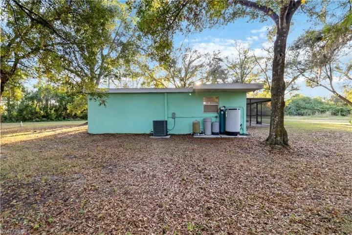 Rear view of house featuring central air condition unit and a sunroom
