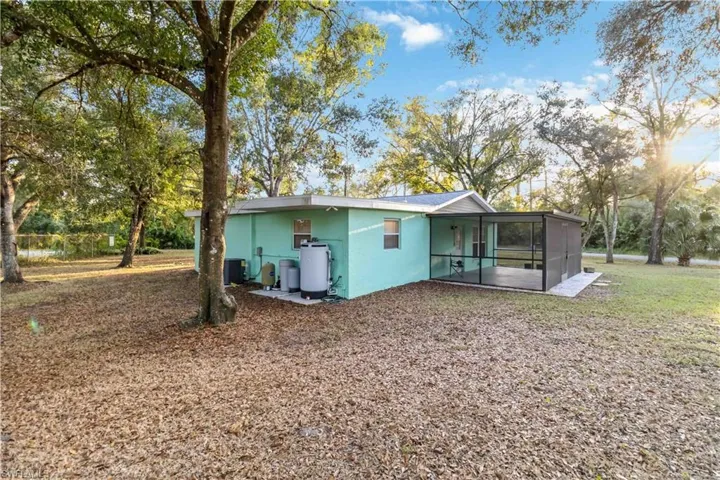 Back of house with central AC unit and a sunroom
