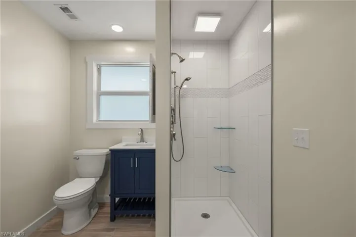 Well-appointed bathroom with a blue vanity and a modern shower space - Virtually Edited Image