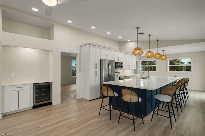 Bright kitchen with a spacious island flowing into the living area - Virtually Edited Image