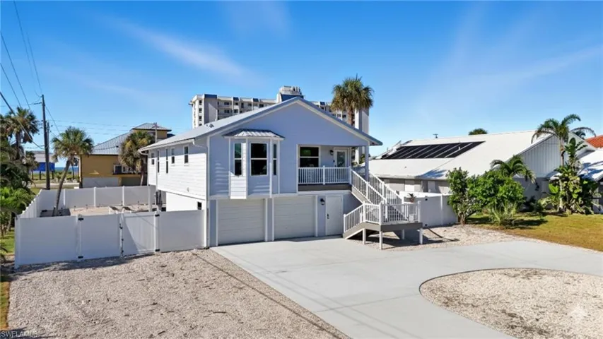 View of front of house featuring a gate, a balcony, concrete driveway, stairway, and a garage - Virtually Edited Image