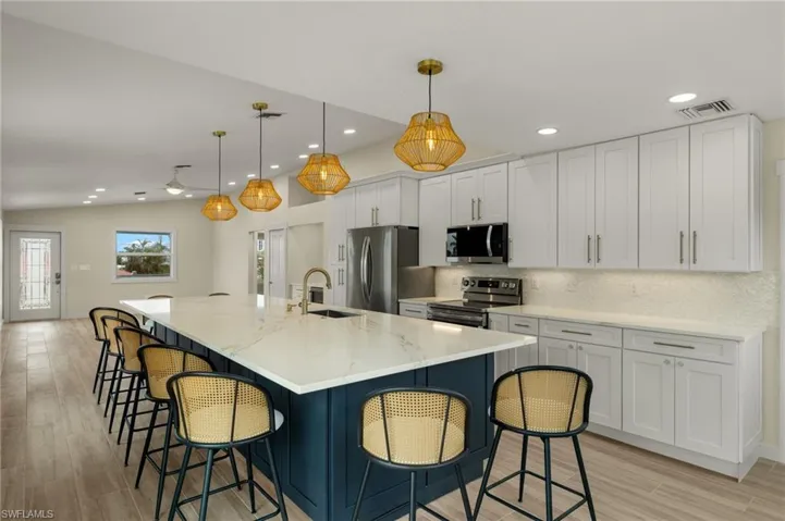 Bright and spacious kitchen with white cabinetry and a center island - Virtually Edited Image