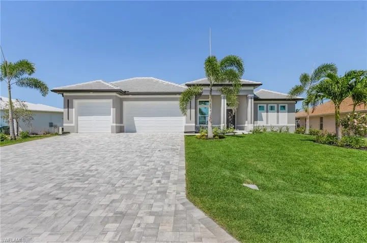 Prairie-style home with an attached garage, decorative driveway, a front lawn, stucco siding, and a tile roof