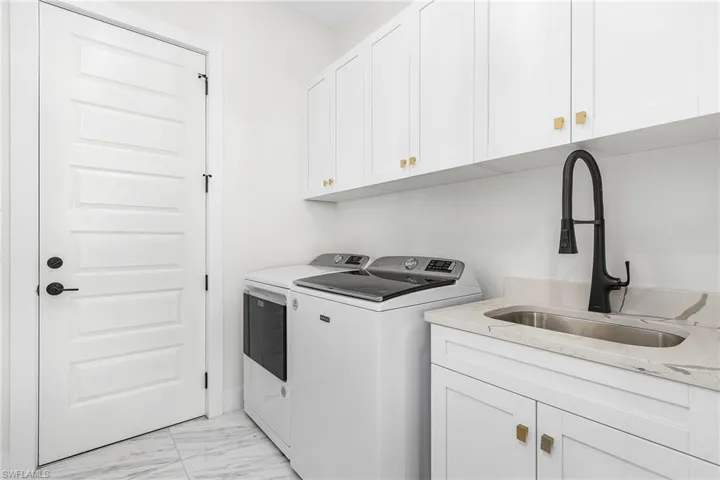 Washroom with separate washer and dryer, cabinet space, and light marble finish floors