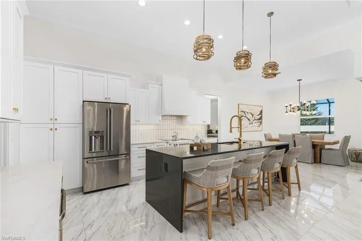 Kitchen featuring high quality fridge, a sink, a chandelier, custom range hood, and light marble finish flooring
