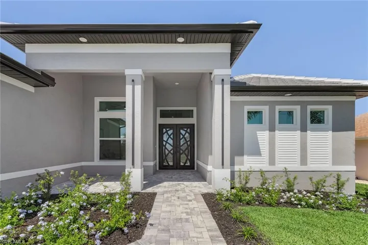 View of exterior entry featuring stucco siding and french doors