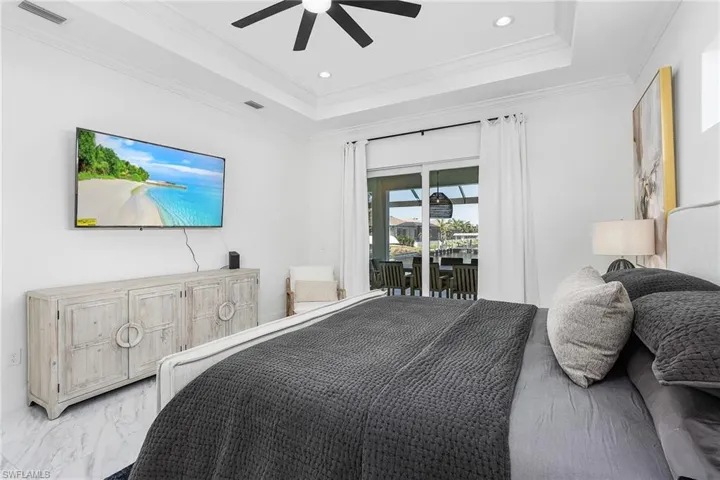 Bedroom featuring a raised ceiling, access to outside, crown molding, light marble finish flooring, and recessed lighting