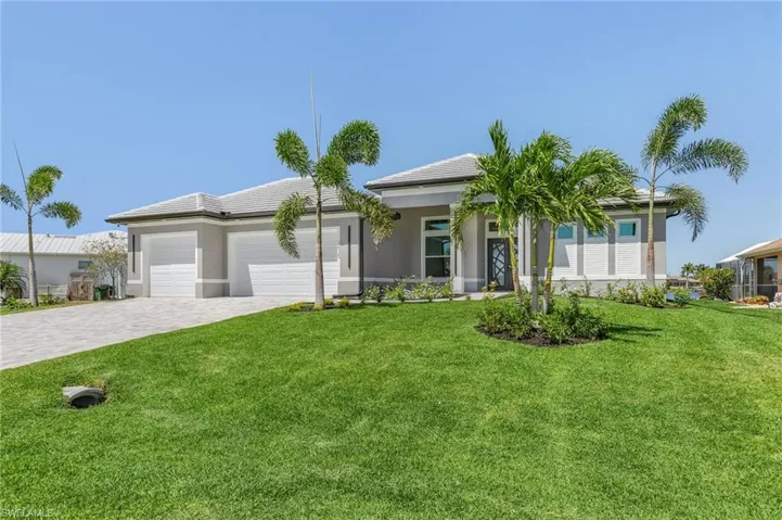 View of front facade featuring decorative driveway, an attached garage, a front lawn, and stucco siding