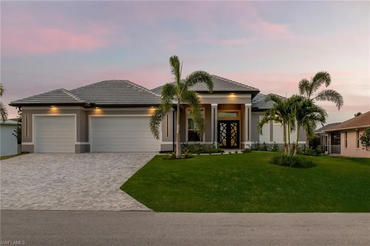 Prairie-style house featuring an attached garage, decorative driveway, a tiled roof, a yard, and stucco siding