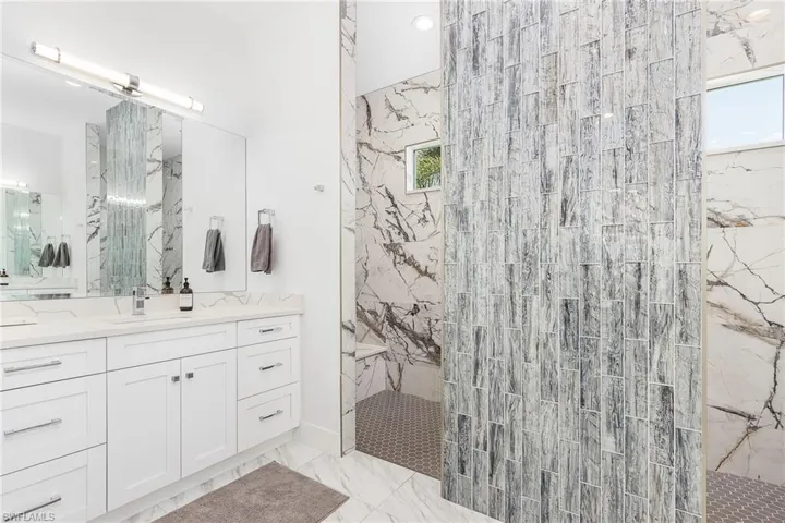 Full bath with marble finish floors, vanity, and a marble finish shower