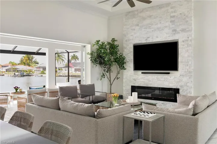 Living room featuring a ceiling fan, a fireplace, and crown molding