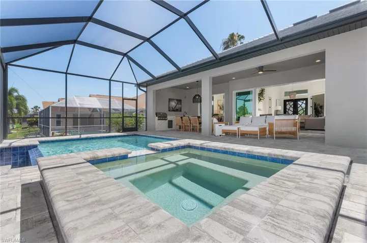 View of pool featuring outdoor lounge area, a patio area, a ceiling fan, a pool with connected hot tub, and a lanai