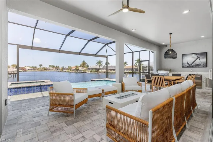 View of patio / terrace featuring an outdoor living space with a fire pit, glass enclosure, a water view, and ceiling fan