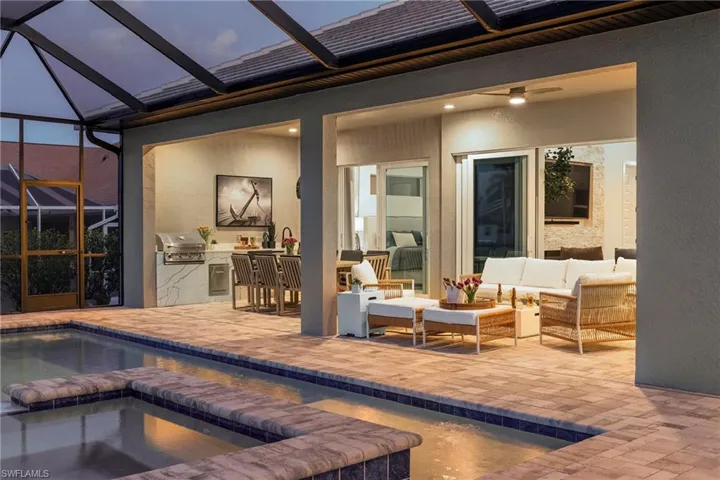 View of pool featuring an outdoor kitchen, a patio, ceiling fan, a lanai, and an outdoor hangout area