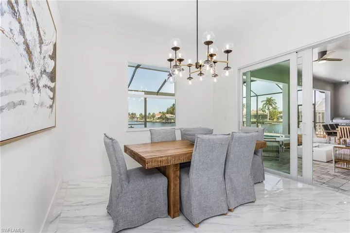 Dining area with marble finish flooring, crown molding, a chandelier, a water view, and baseboards