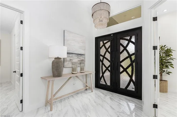 Entryway with marble finish floors, a chandelier, baseboards, and crown molding