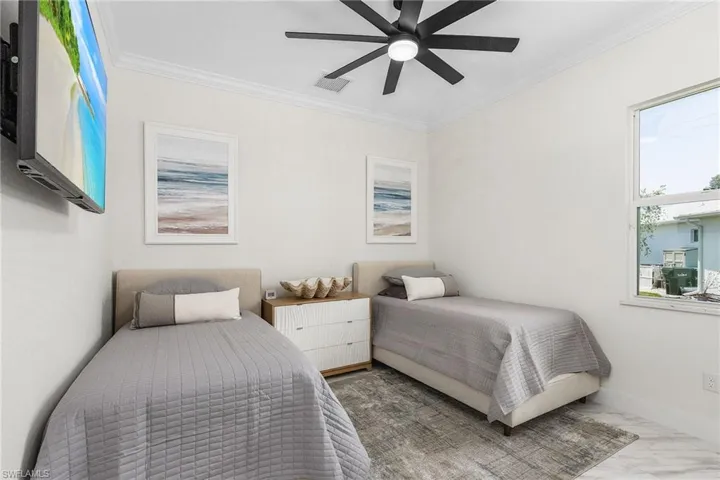 Bedroom with marble finish floors, crown molding, and ceiling fan