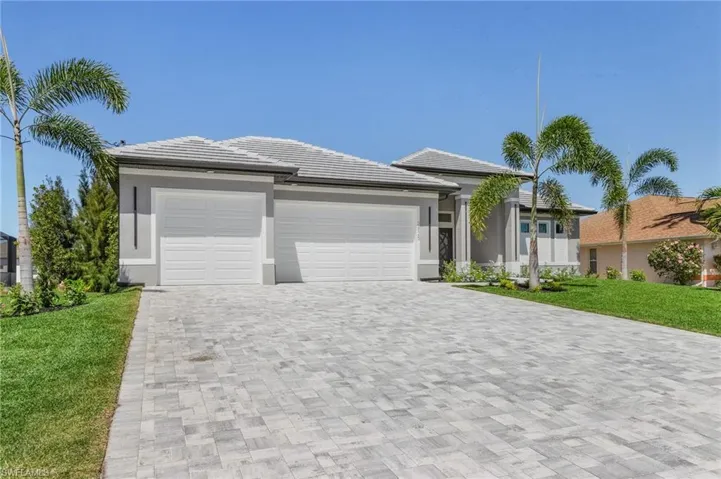 View of front of house with a garage, decorative driveway, a front yard, stucco siding, and a tiled roof