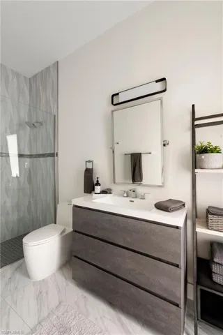Full bath featuring a tile shower, vanity, and marble finish floors