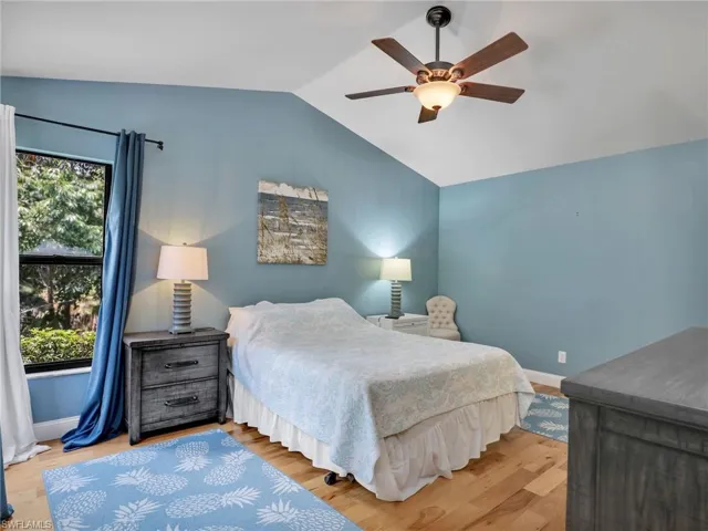 Bedroom with ceiling fan, baseboards, vaulted ceiling, and wood finished floors