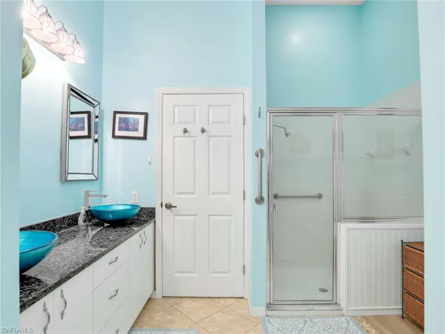 Bathroom with double vanity, tile patterned flooring, a stall shower, a sink, and baseboards