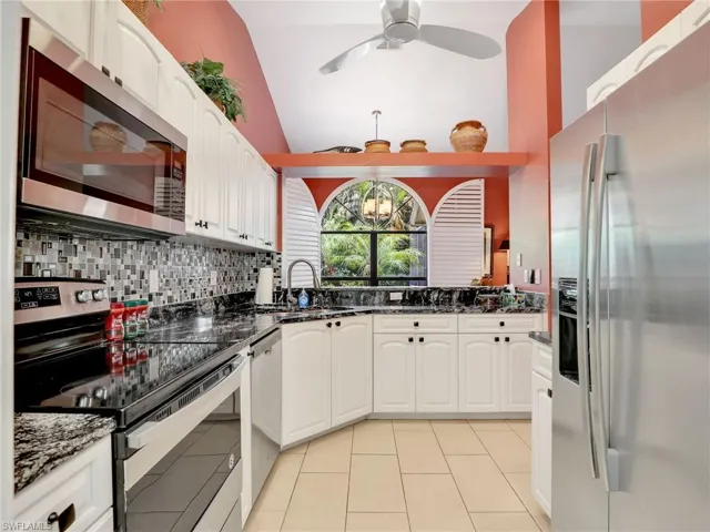 Kitchen with tasteful backsplash, a sink, white cabinets, dark stone countertops, and stainless steel appliances