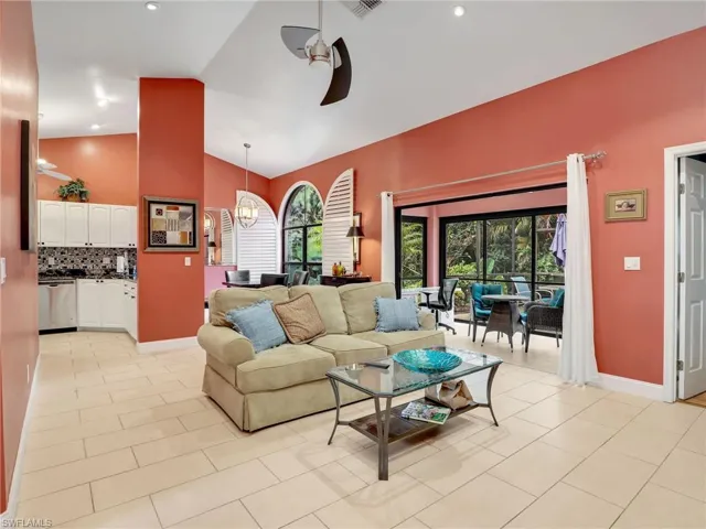 Living area with baseboards, a ceiling fan, light tile patterned floors, and high vaulted ceiling