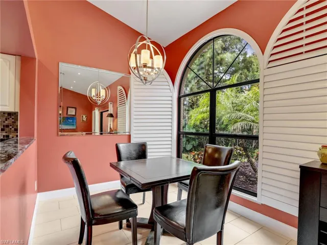 Dining space featuring light tile patterned floors, baseboards, vaulted ceiling, and a notable chandelier