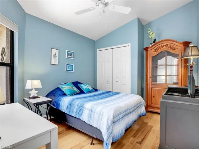 Bedroom with a ceiling fan, light wood-style flooring, lofted ceiling, and a closet