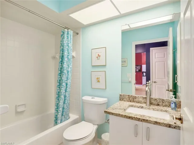 Bathroom with vanity, shower / bath combination with curtain, and toilet