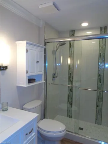 Full bath featuring vanity, a stall shower, recessed lighting, and ornamental molding