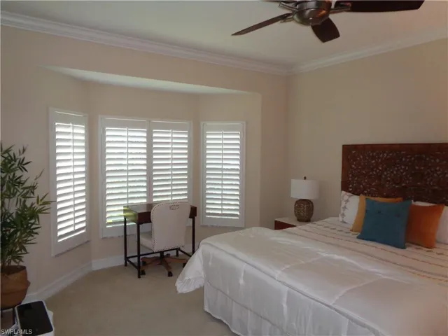 Carpeted bedroom with crown molding and a ceiling fan