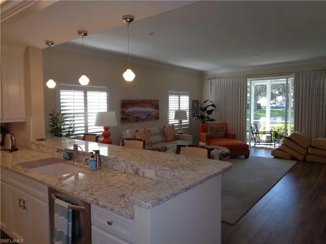 Kitchen featuring open floor plan, a peninsula, white cabinets, ornamental molding, and dark wood-style flooring