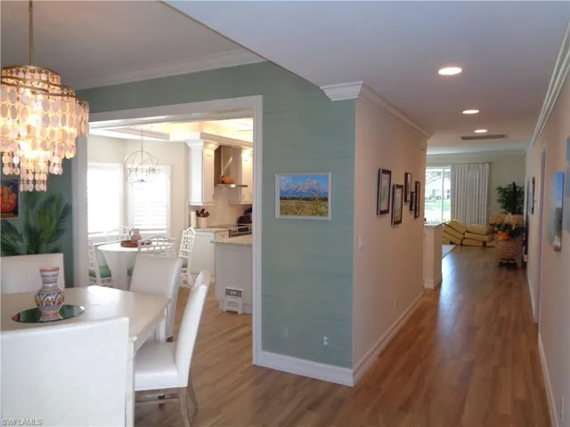 Dining area with ornamental molding, wood finished floors, a chandelier, and recessed lighting