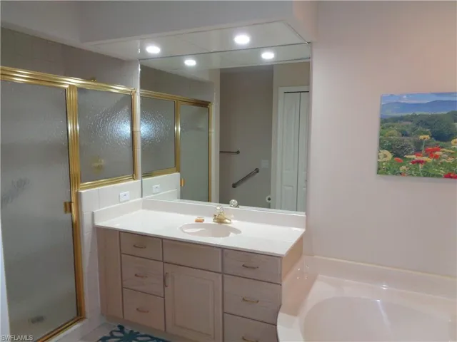 Full bathroom featuring a stall shower, vanity, a bath, and recessed lighting