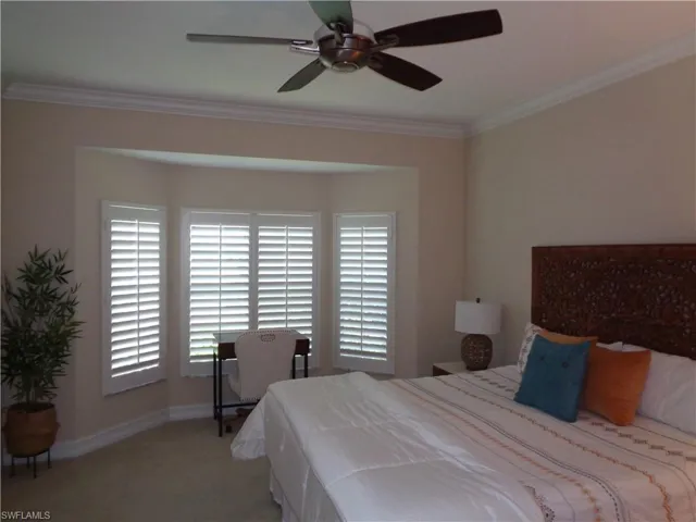 Bedroom with ornamental molding, multiple windows, carpet flooring, and a ceiling fan