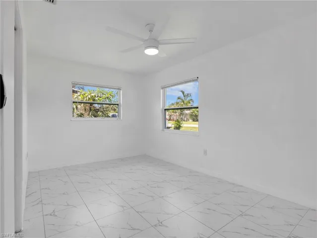 White tile flooring with a subtle veined pattern, bright white walls, and two windows providing natural light