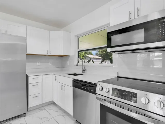 Contemporary kitchen featuring white cabinetry, light-colored countertops, a tile backsplash, and stainless steel appliances