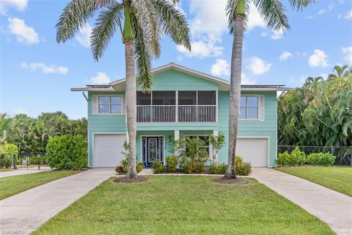 View of front of property featuring a garage, concrete driveway, and a balcony