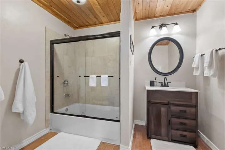 Full bathroom featuring bath / shower combo with glass door, vanity, wooden ceiling, and light wood-style floors