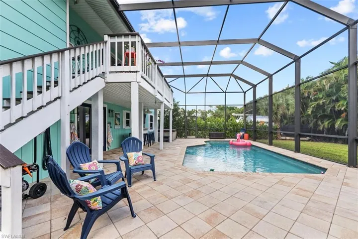Swimming pool featuring a sunroom, a patio area, and glass enclosure