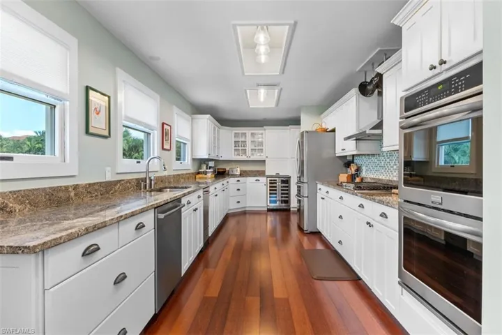 Kitchen with appliances with stainless steel finishes, healthy amount of natural light, white cabinetry, and dark stone counters