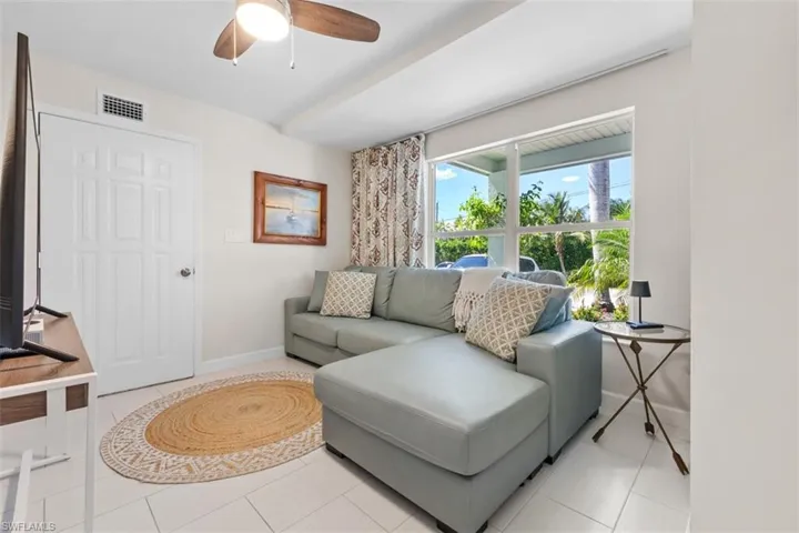 Den with light tile patterned floors and ceiling fan