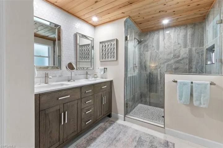 Master Bathroom with wood ceiling, a stall shower, double vanity, and light tile patterned flooring
