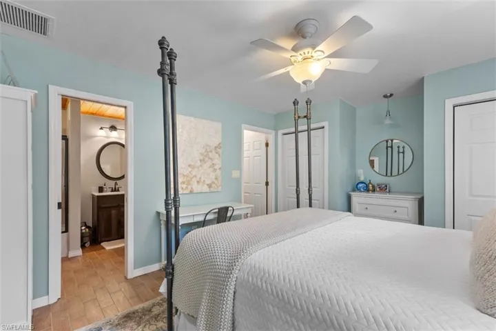 Bedroom with two closets, light wood-style flooring, ceiling fan, and ensuite bathroom