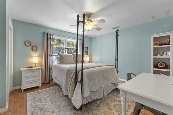 Bedroom with light wood-style flooring, ceiling fan, and a desk