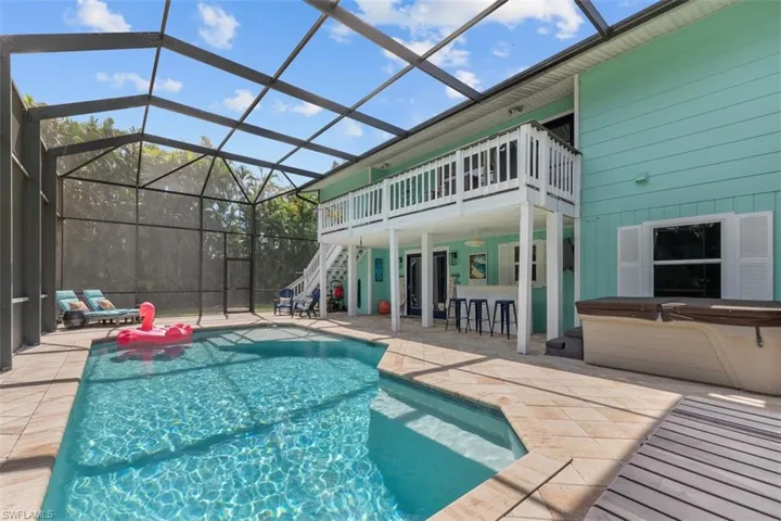 Swimming pool with a lanai, a patio area, a sunroom, and a hot tub