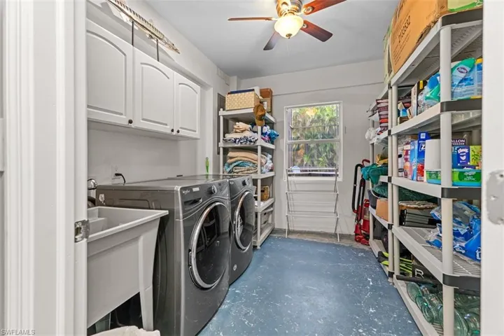 Laundry room featuring cabinet space, washer and clothes dryer, concrete flooring, and a ceiling fan